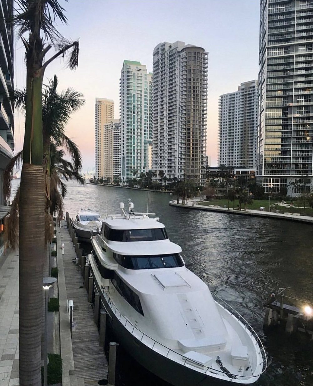 Yachts docked on the Miami River with the Brickell towers above at dusk