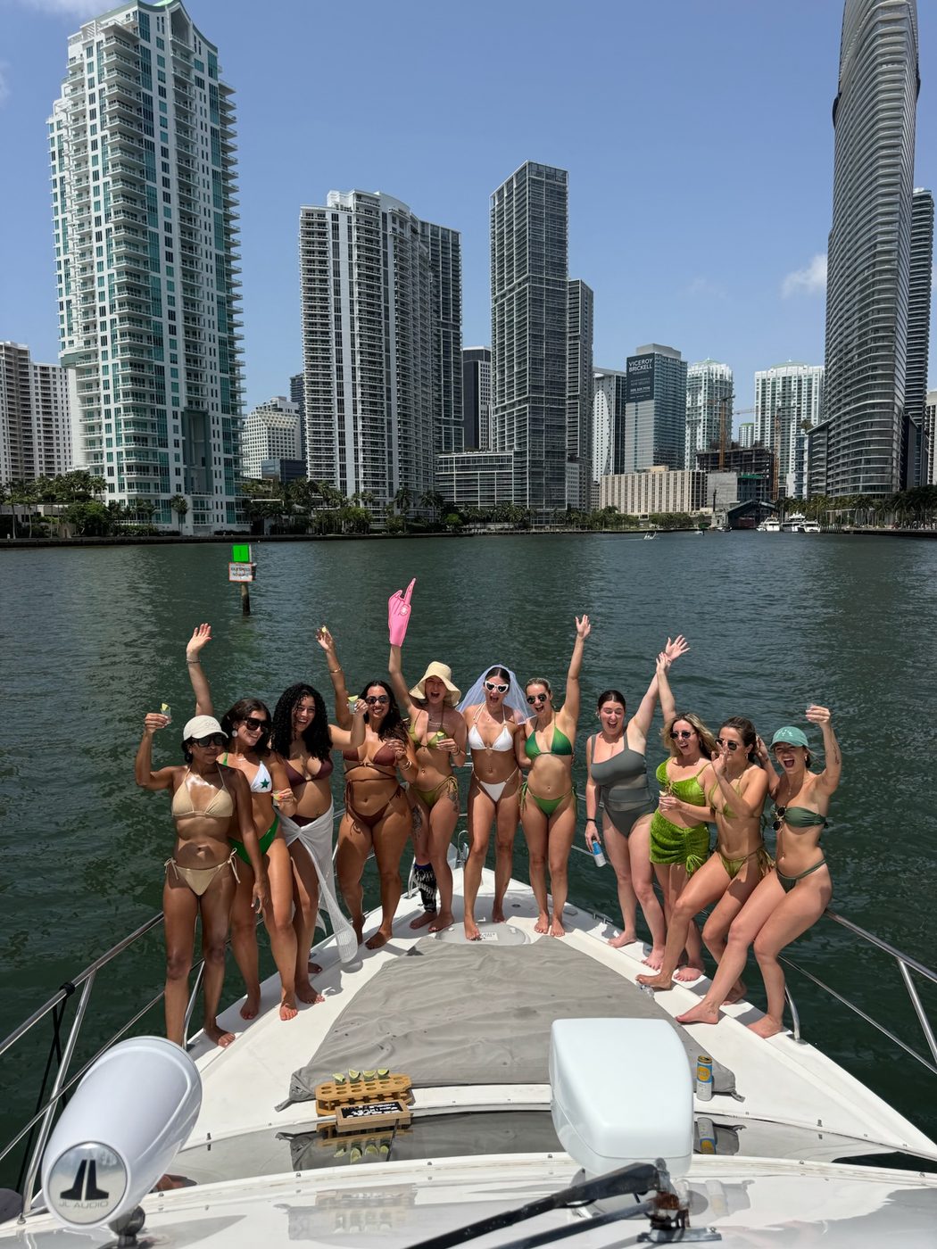 Bride and bachelorette group toasting on a yacht bow with the Miami skyline behind