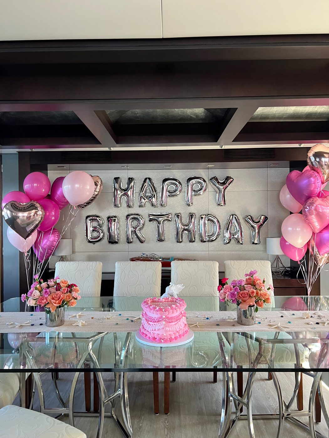 Birthday cake and pink balloons set up in a yacht salon in Miami