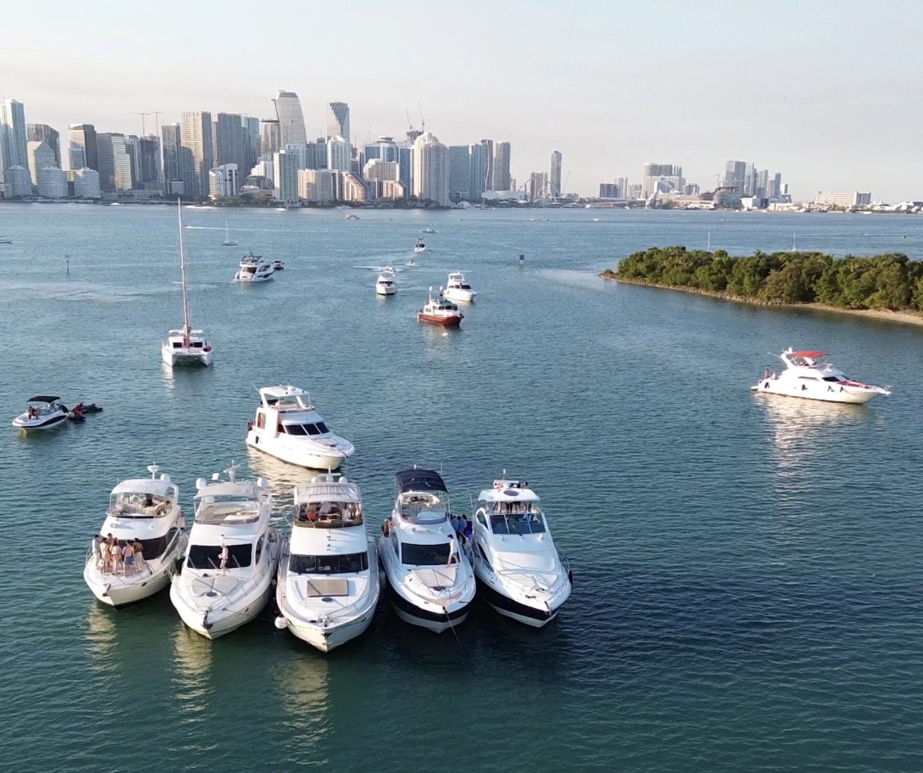 Five yachts rafted together on Biscayne Bay with the Brickell skyline behind