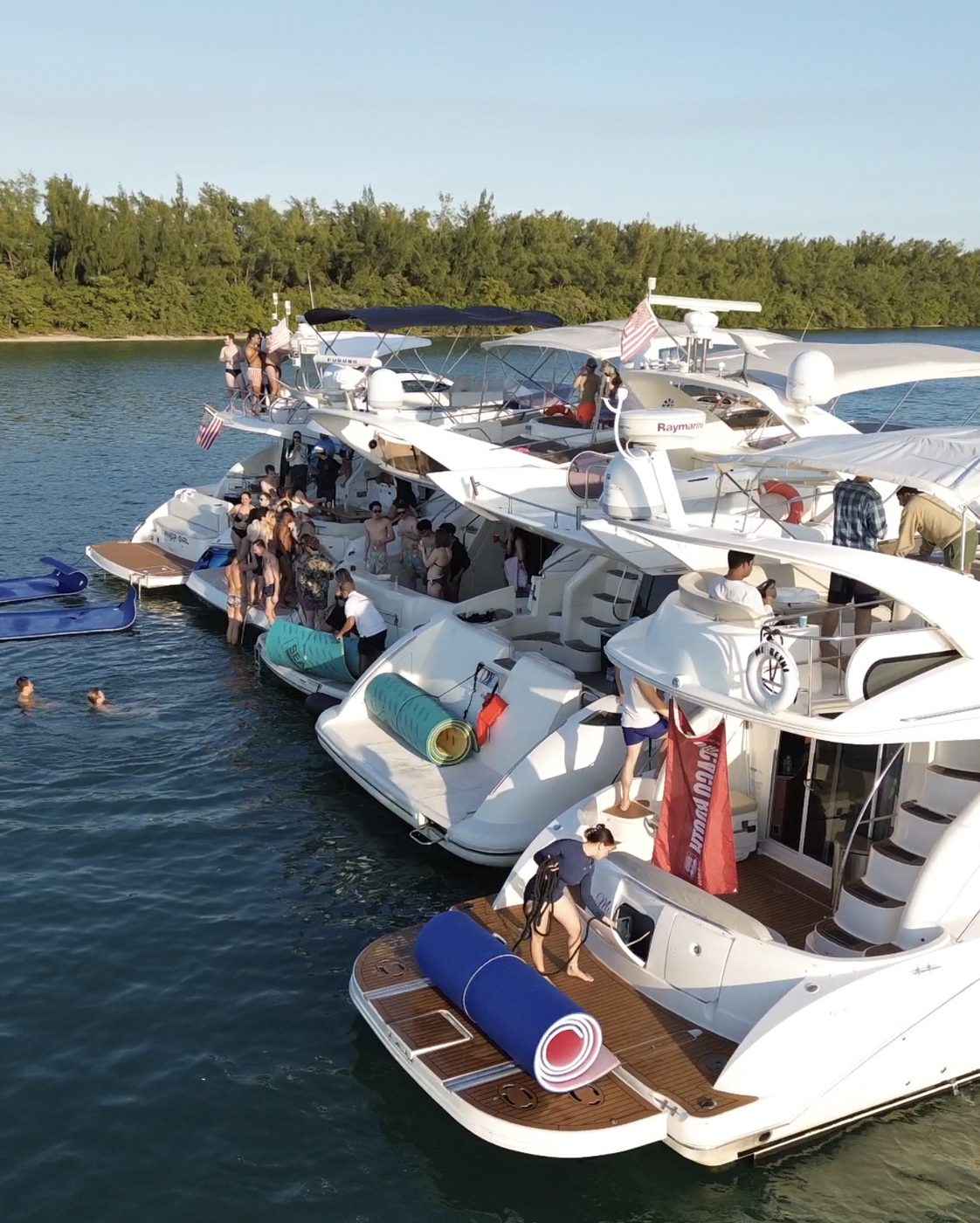 Corporate group moving between yachts tied together at a Miami sandbar